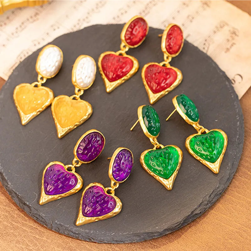 Oval-shaped love heart stud earrings with a pleated silver texture in purple, red, green, and yellow/white colours.