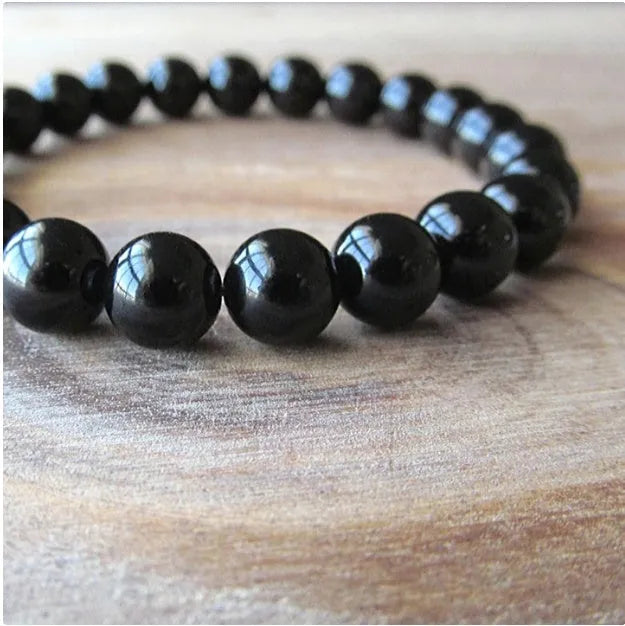A geometric black onyx bracelet for women with 8mm beads on an elastic cord.