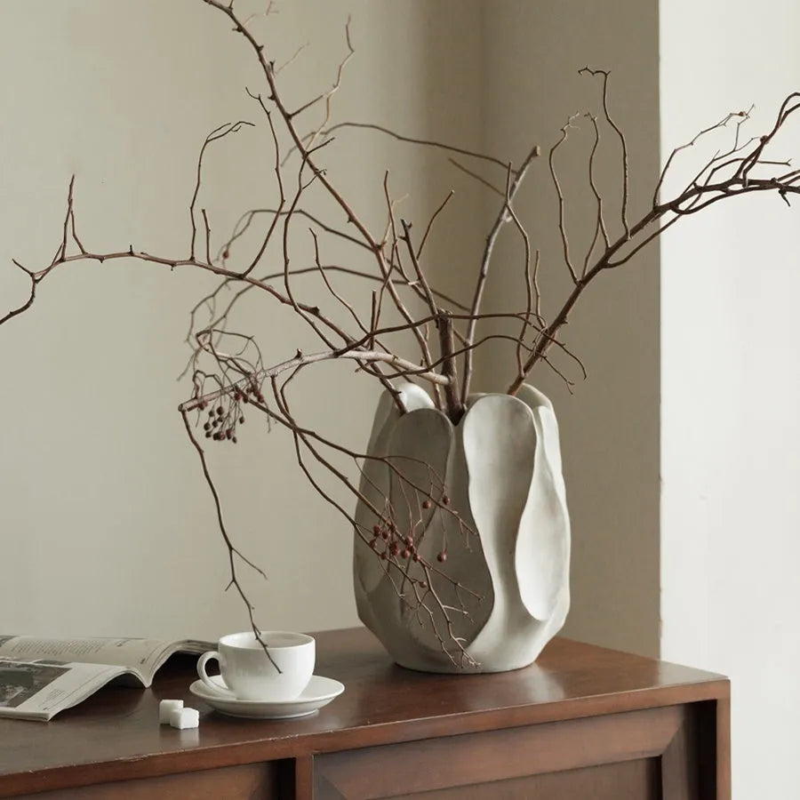 Handmade irregular shaped ceramic vase in natural glaze on a wooden surface.