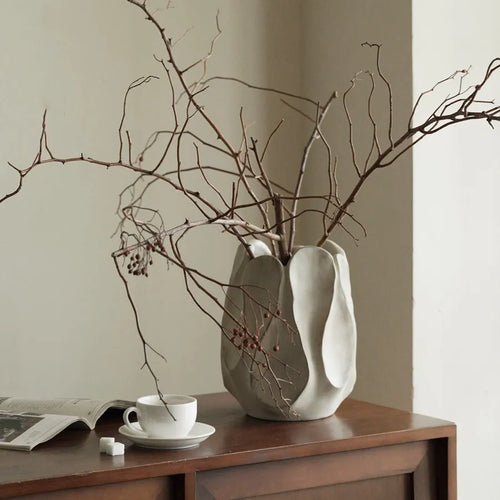 Handmade irregular shaped ceramic vase in natural glaze on a wooden surface.