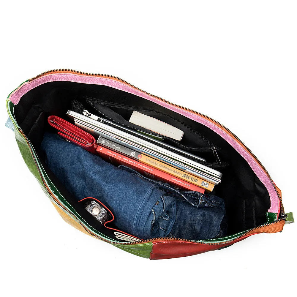 Brown cowhide leather crossbody travel bag with stitching detail, shown with a laptop and magazine.