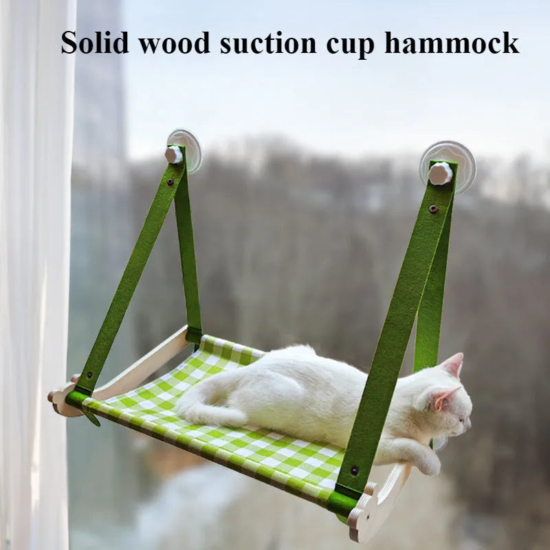 Pink wooden cat hammock with suction cups attached to a window, showing a cat resting on the linen fabric.