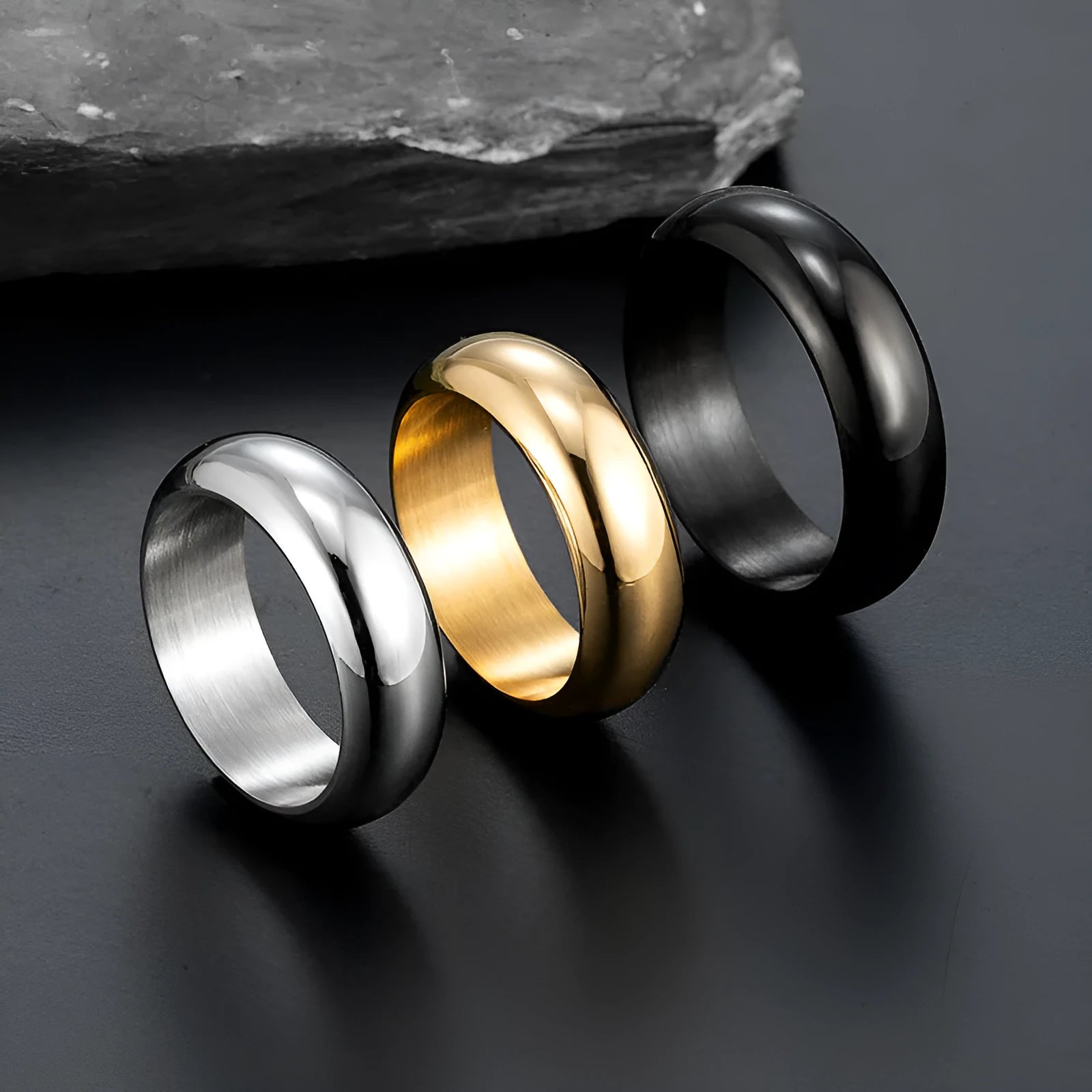 Glossy electroplated titanium steel ring shown in gold, black, and steel colour finishes on a grey background.