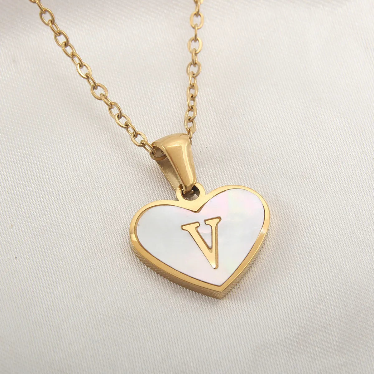 Gold-plated heart necklace with white shell pendant personalised with a letter, on an adjustable chain.