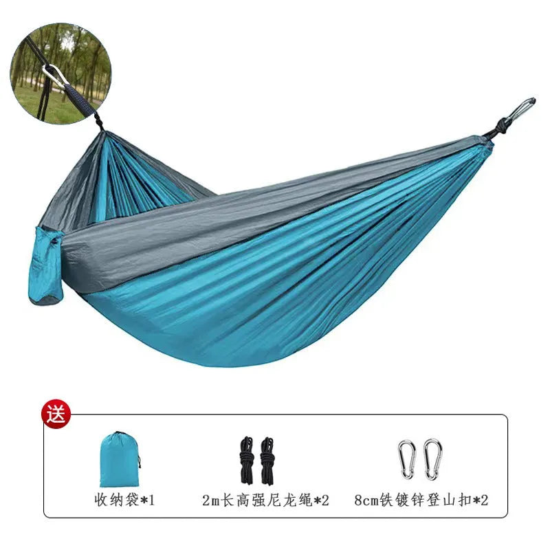 Blue parachute nylon camping hammock hanging between trees with 300kg capacity
