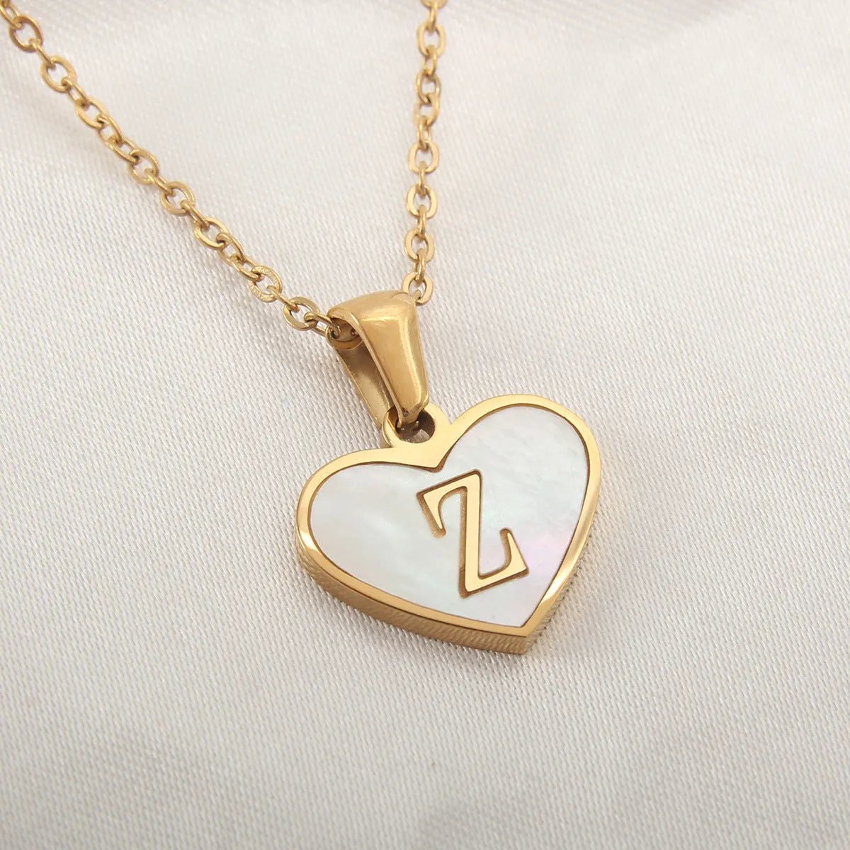 Gold-plated heart necklace with white shell pendant personalised with a letter, on an adjustable chain.
