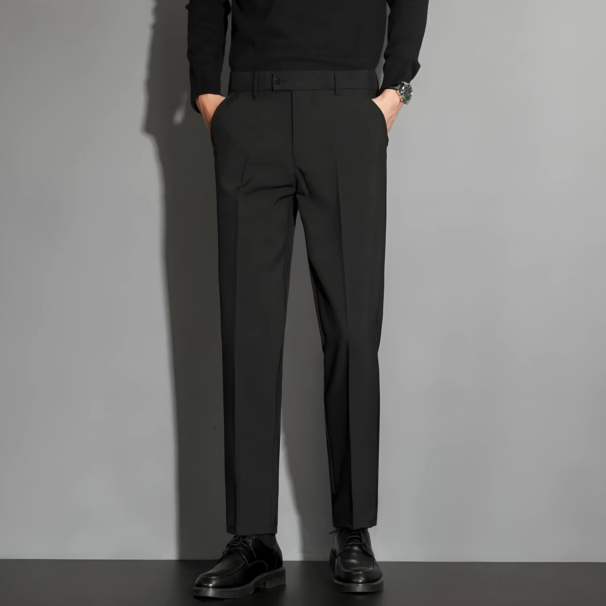 Man wearing straight leg ankle-length suit trousers in a light colour, showing the drape of the fabric.