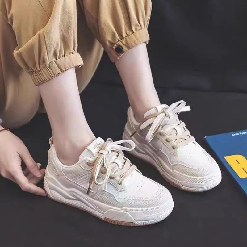 Pink and beige low top women's sneakers with a rubber sole on a neutral background.