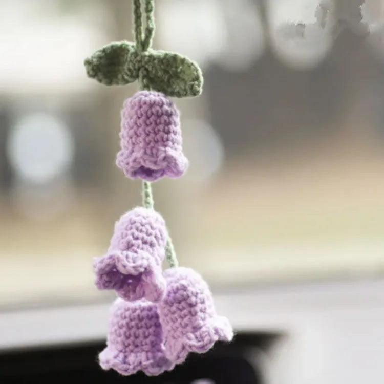 Green and white knitted wool car plant decoration with hanging rope on car dashboard