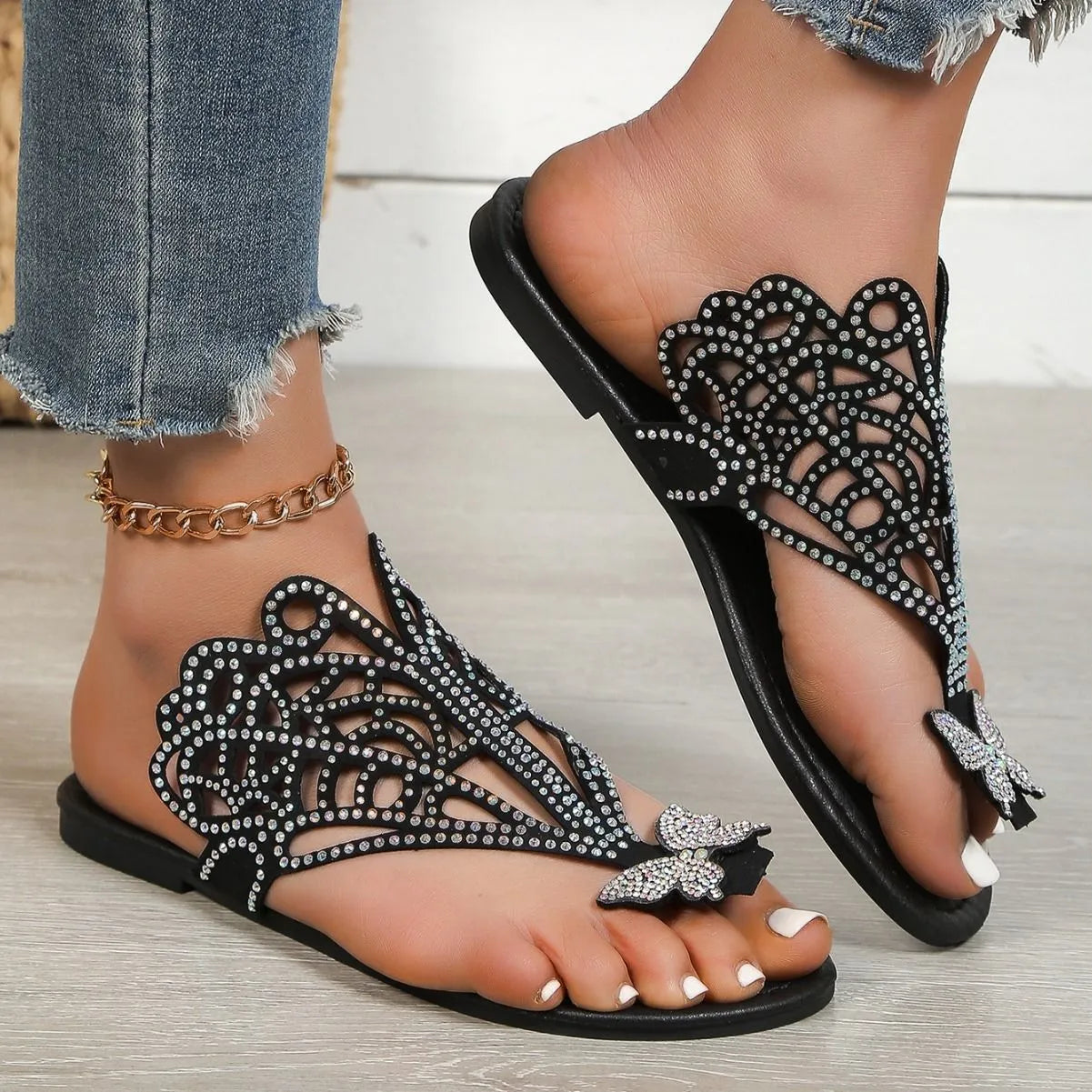 Women's black slip-on sandals with rhinestone decoration on the flip-toe and a flat rubber sole.