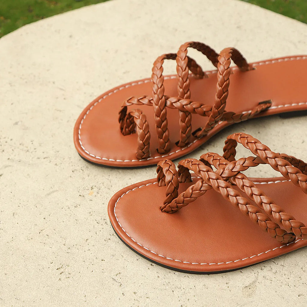 Women's white clip-toe woven flat sandals with a rubber sole on a neutral background.