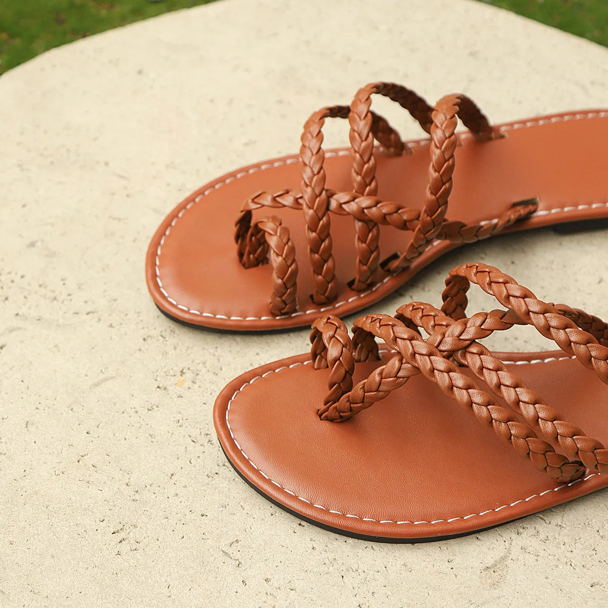 Women's white clip-toe woven flat sandals with a rubber sole on a neutral background.