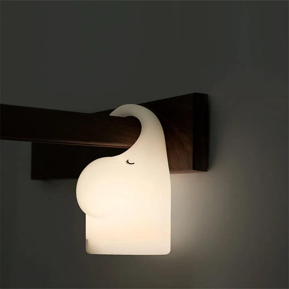DOMI soft silicone elephant night light on a bedside table emitting warm white glow