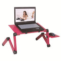 Black folding metal laptop bed table with cooling fans extended over a sofa
