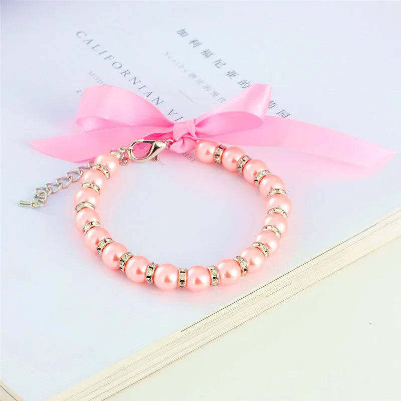 Adjustable diamond dog pearl necklace with rhinestones and ribbon bow in blue, pink, purple, or white.