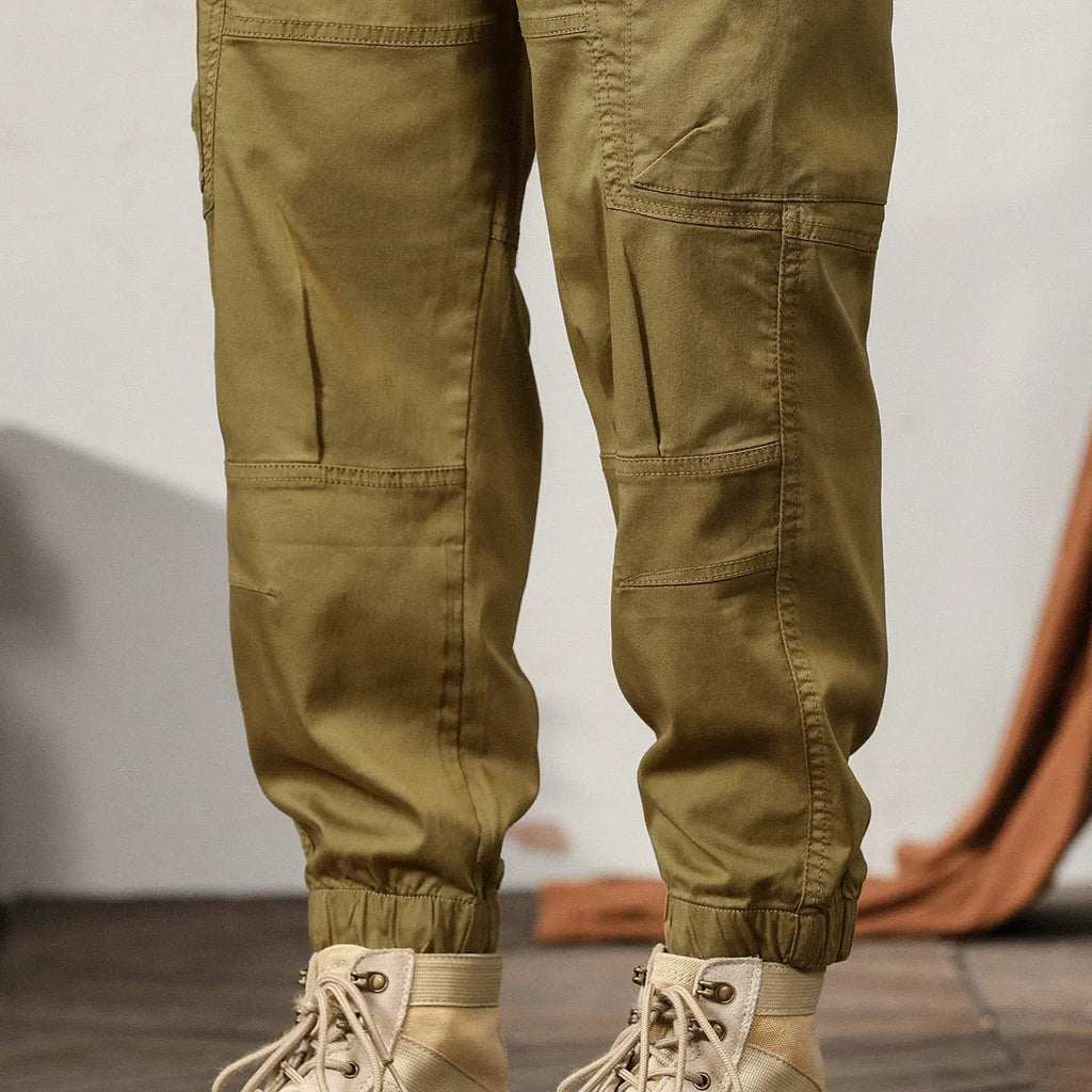 Men's khaki cotton tapered harem pants with an ankle band and loose fit.
