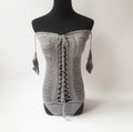 Women's white off-the-shoulder one-piece swimsuit on a mannequin, showing the neckline design.