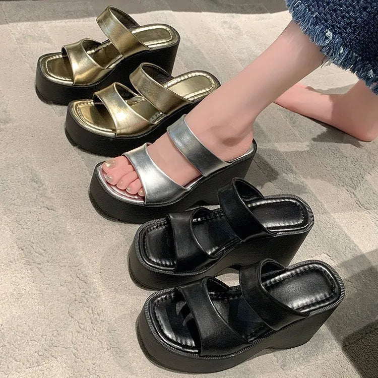 Women's black platform wedge slippers with a square toe design on a white background.