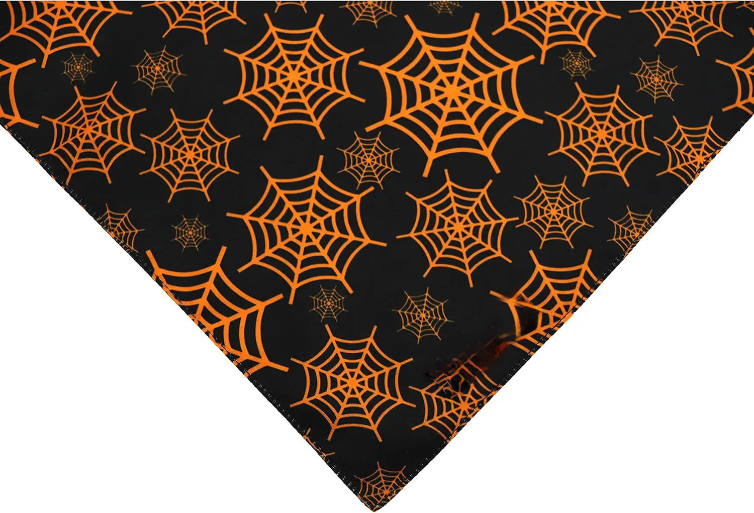 Black and orange reversible Halloween dog bandana with pumpkin and spider web patterns lying flat.