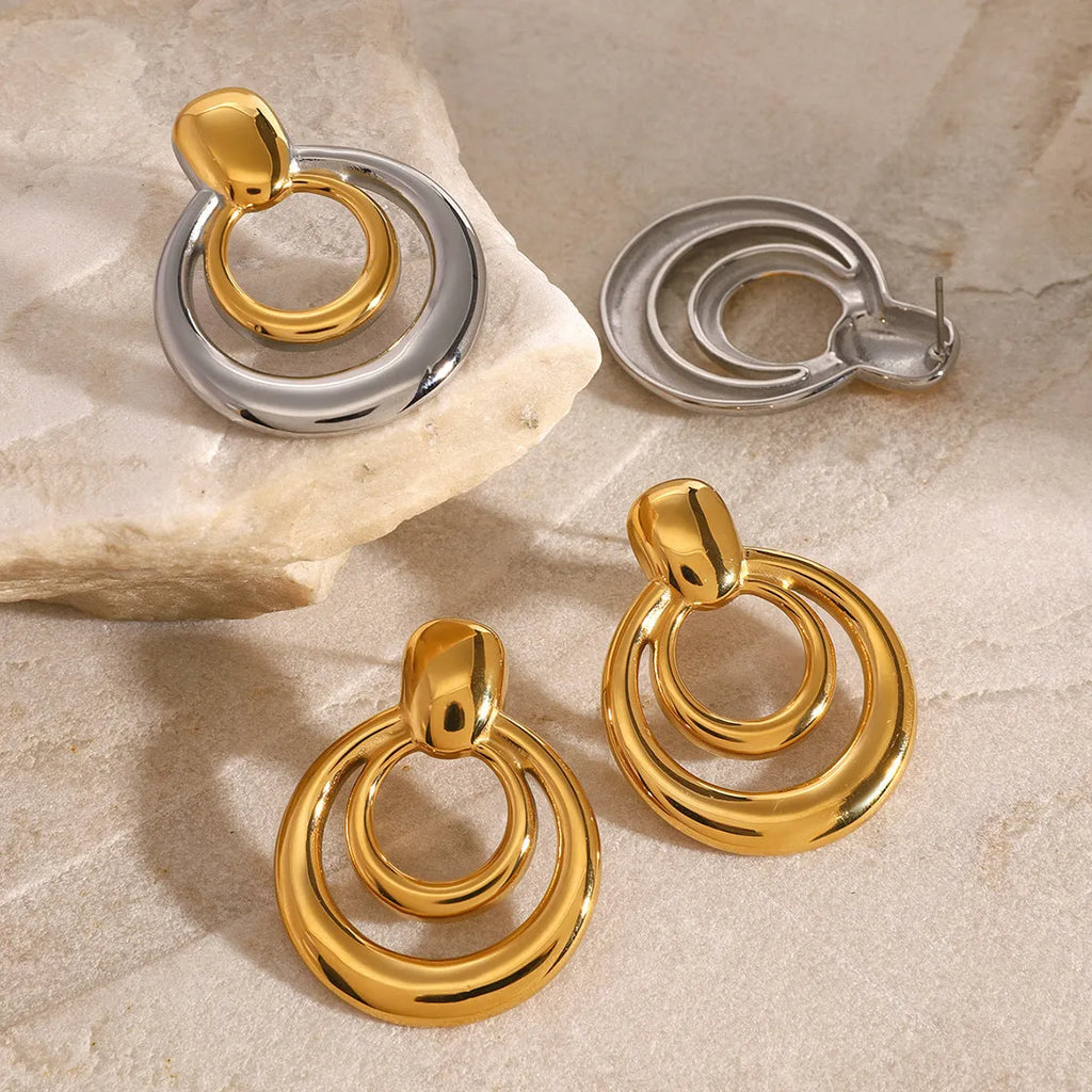 Round double layer hollow stud earrings with a gold electroplated finish on a titanium steel base.