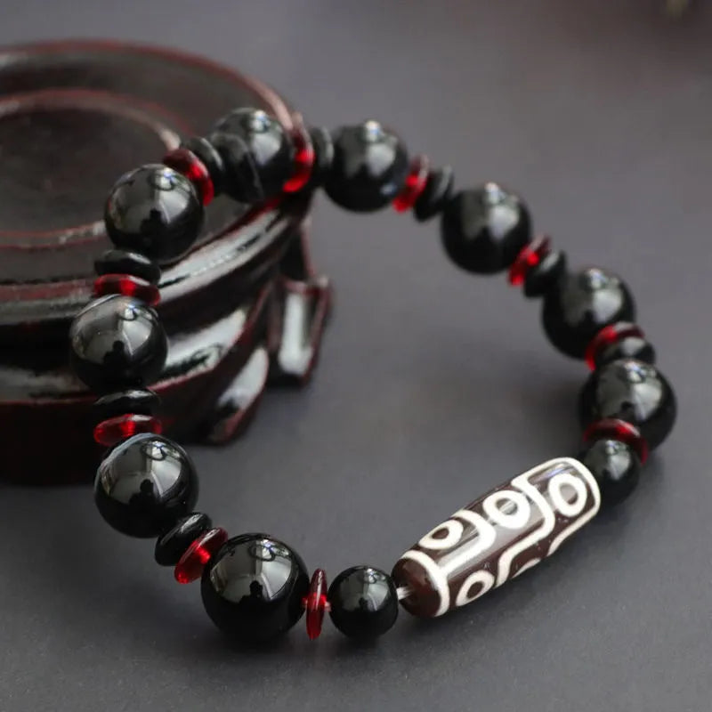 Close-up of a hand-woven black agate bracelet with 11mm geometric beads featuring traditional dzi patterns.