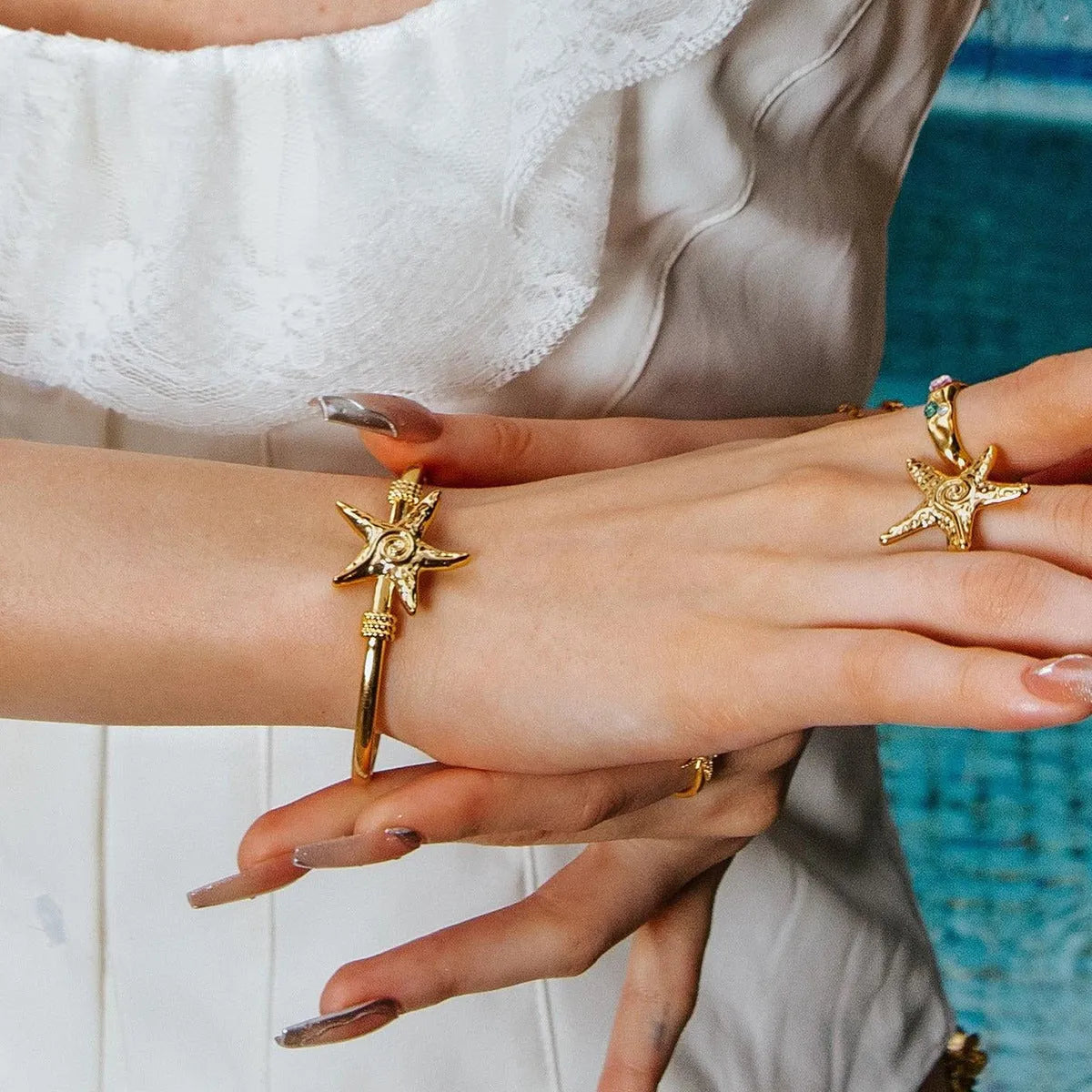 Stainless steel open-ended bracelet with starfish charm on a flat surface