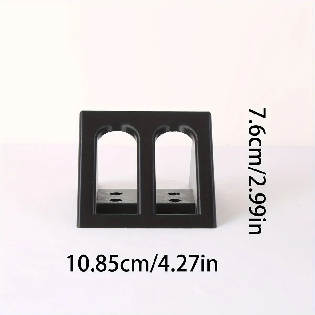 Black punk-style plastic pistol display stand on a surface, showing its compact size and cradle design.