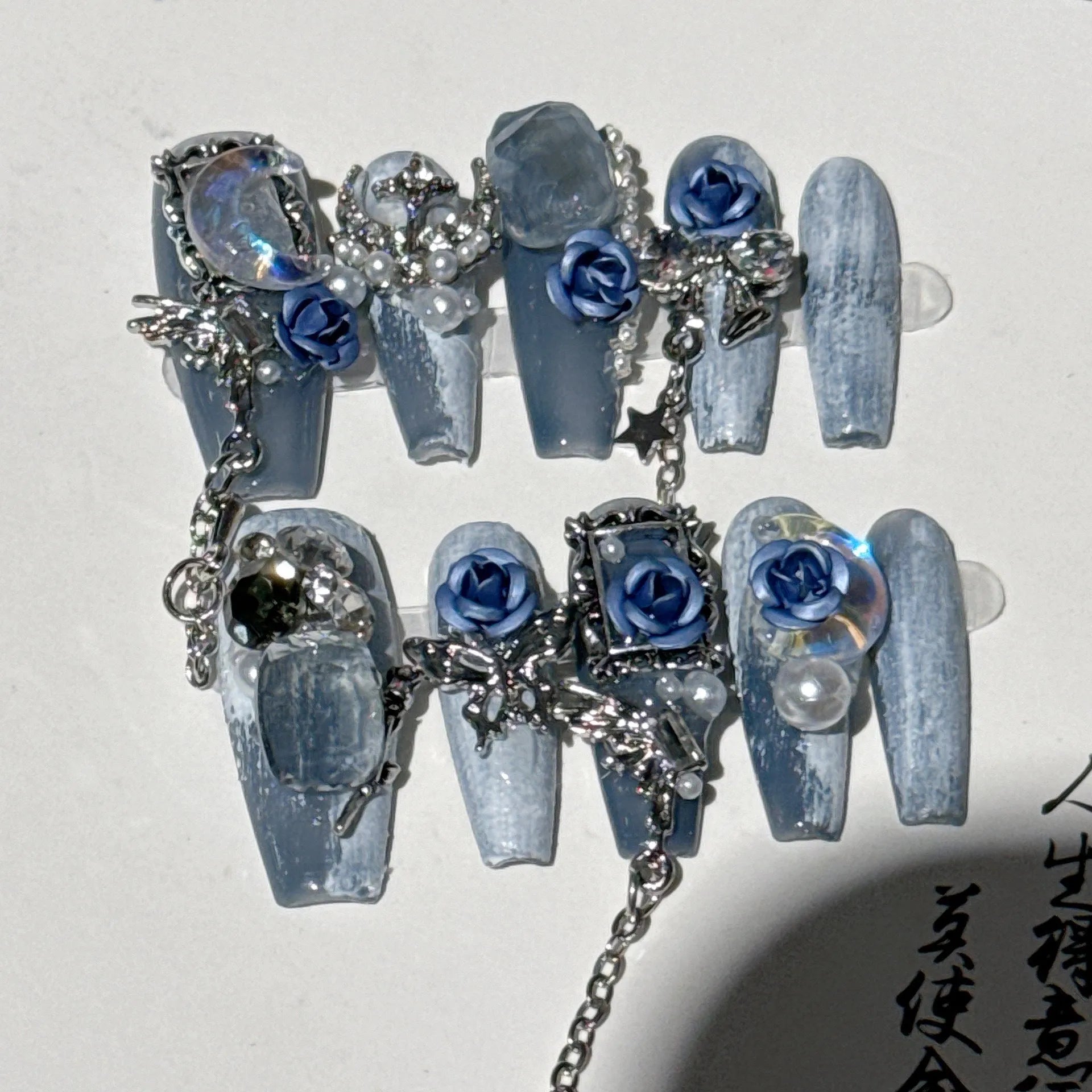 Women's ornate rose floral pattern manicure nails in heavy industry blue colour on a plastic armour suit.