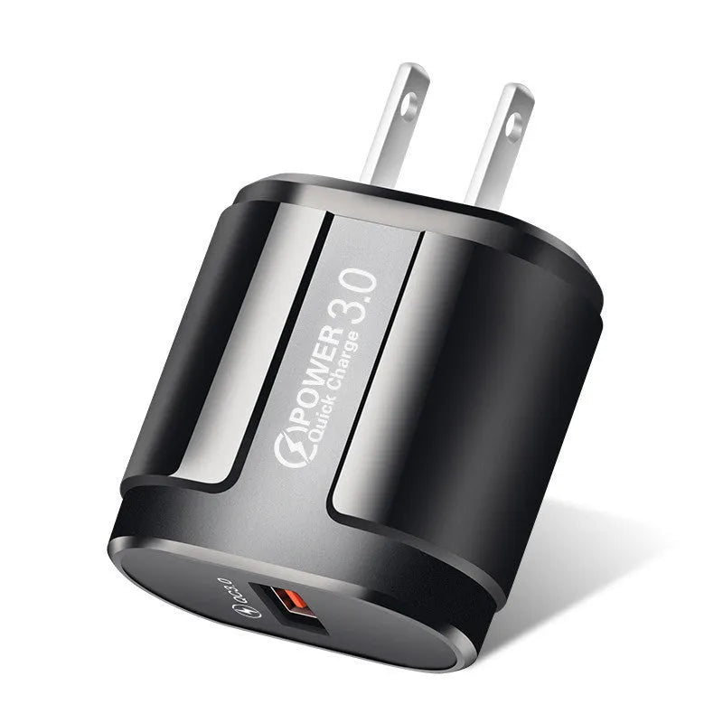 Compact white international travel phone charger with UK, US, and EU plug adapters on a desk