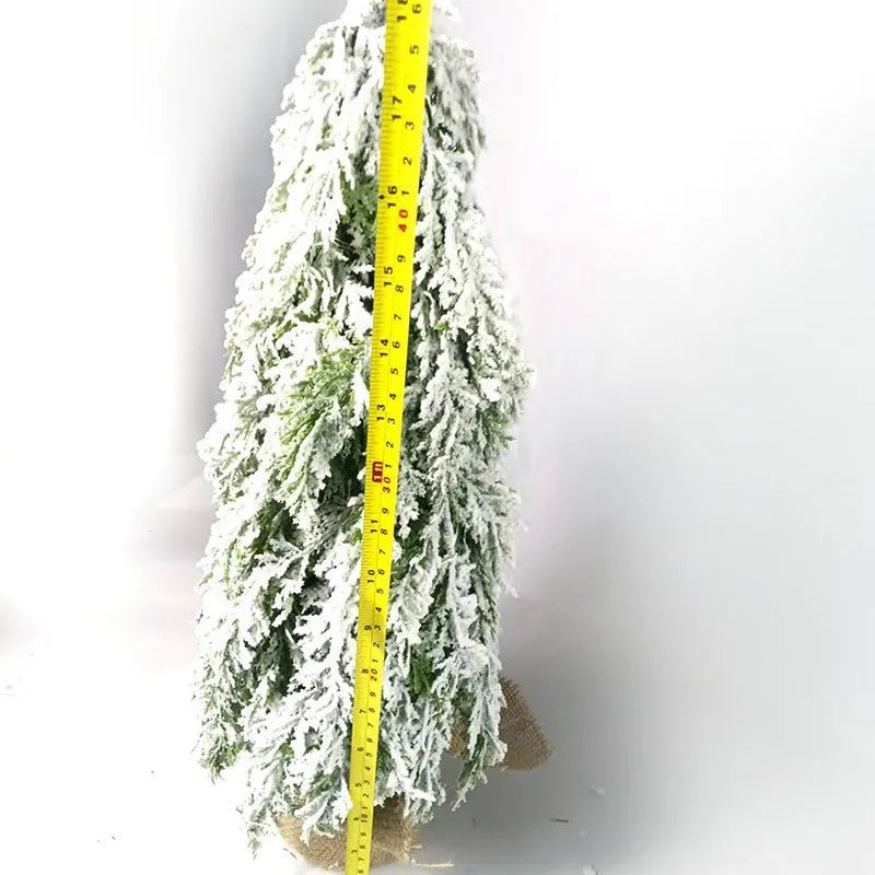 Small white artificial Christmas tree with snowy textured branches and built-in lights on a desktop