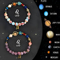 Set of two natural stone beaded bracelets with zodiac sign charms on a table.