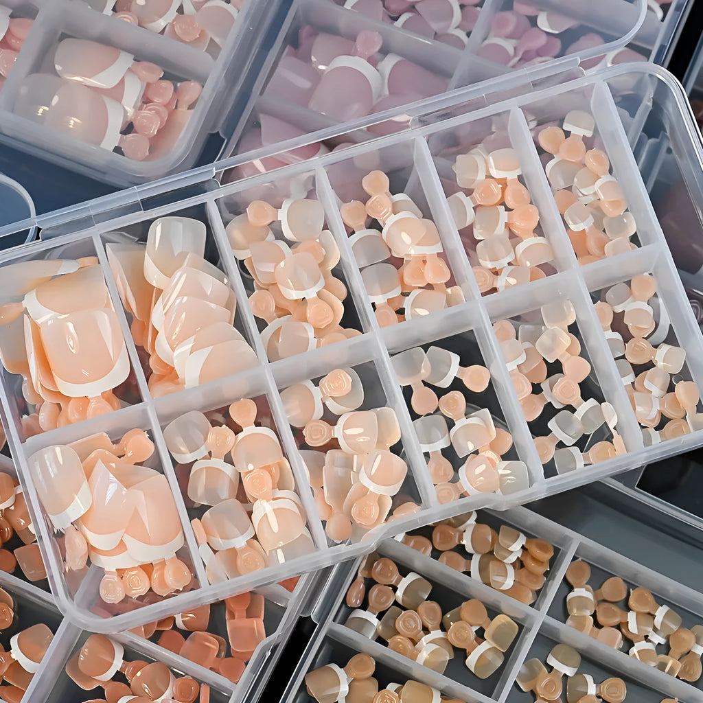 Box of 120 French white edge press-on toe nails in full square short shape showing multiple nude shades.