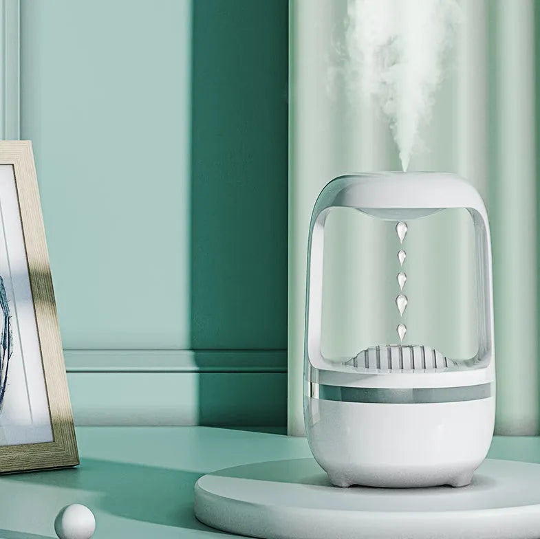 White anti-gravity humidifier with water droplet effect on a desk next to a USB cable.