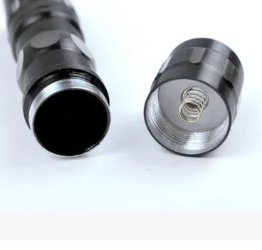 Black aluminium alloy mini LED flashlight showing compact size next to a AA battery for scale.