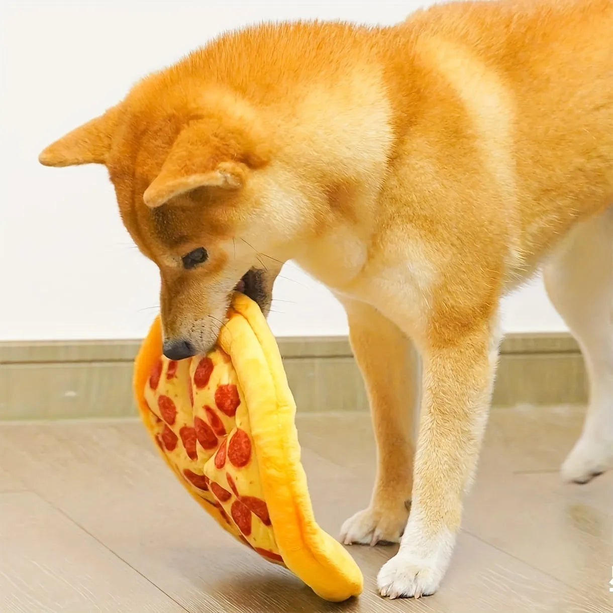 Yellow pizza slice shaped squeaky dog chewing toy with textured toppings and crust detailing