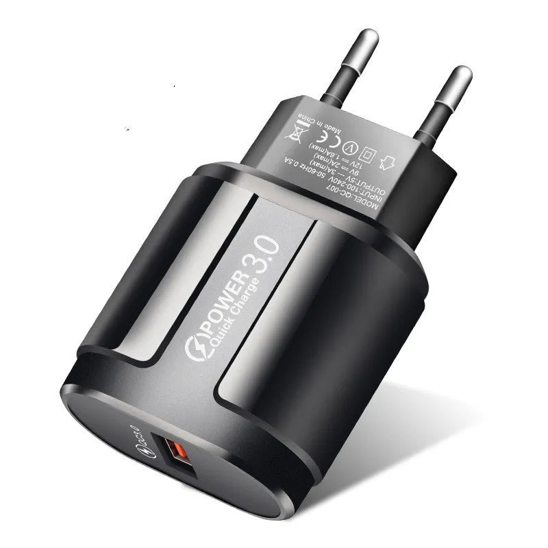 Compact white international travel phone charger with UK, US, and EU plug adapters on a desk