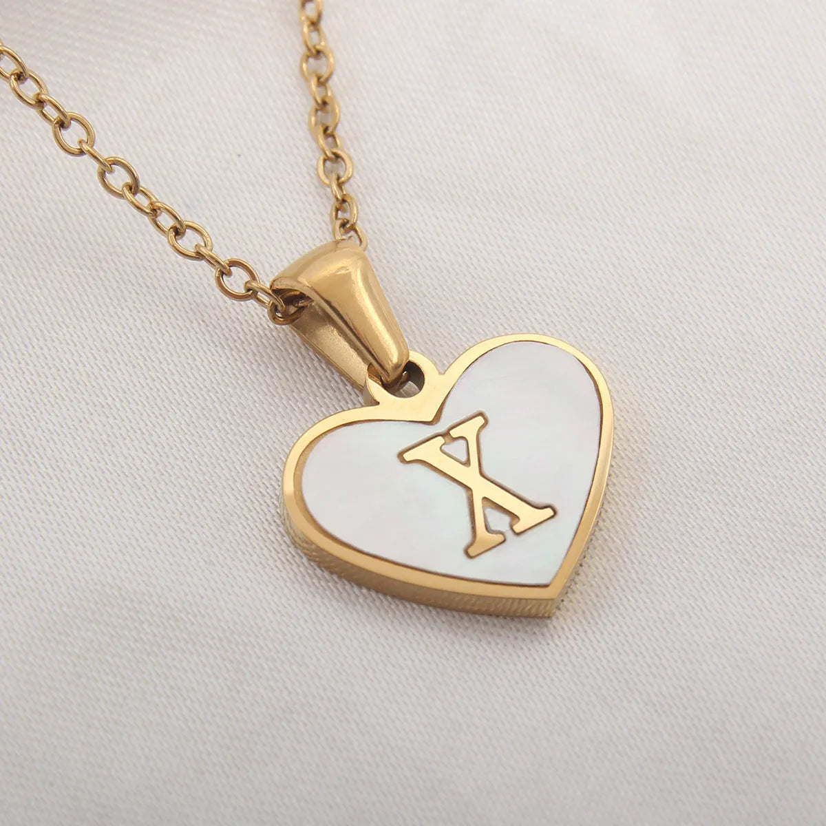 Gold-plated heart necklace with white shell pendant personalised with a letter, on an adjustable chain.