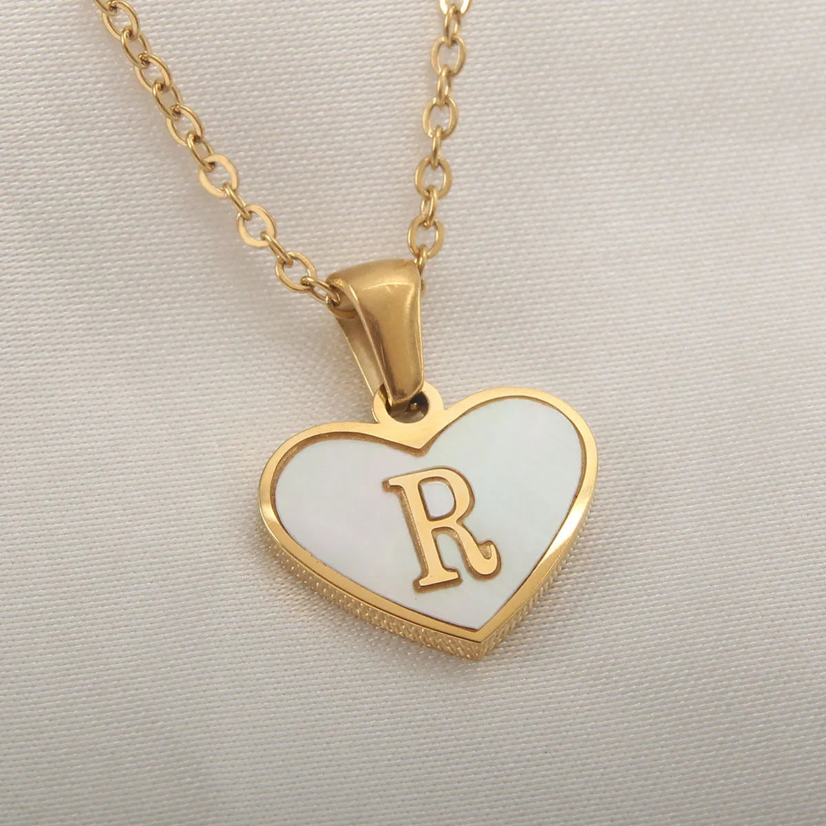 Gold-plated heart necklace with white shell pendant personalised with a letter, on an adjustable chain.