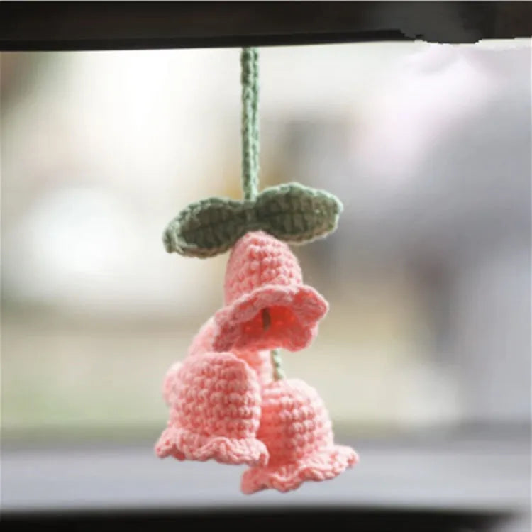 Green and white knitted wool car plant decoration with hanging rope on car dashboard