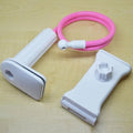 Black aluminium alloy phone holder with flexible arm on a wooden table holding a mobile phone.