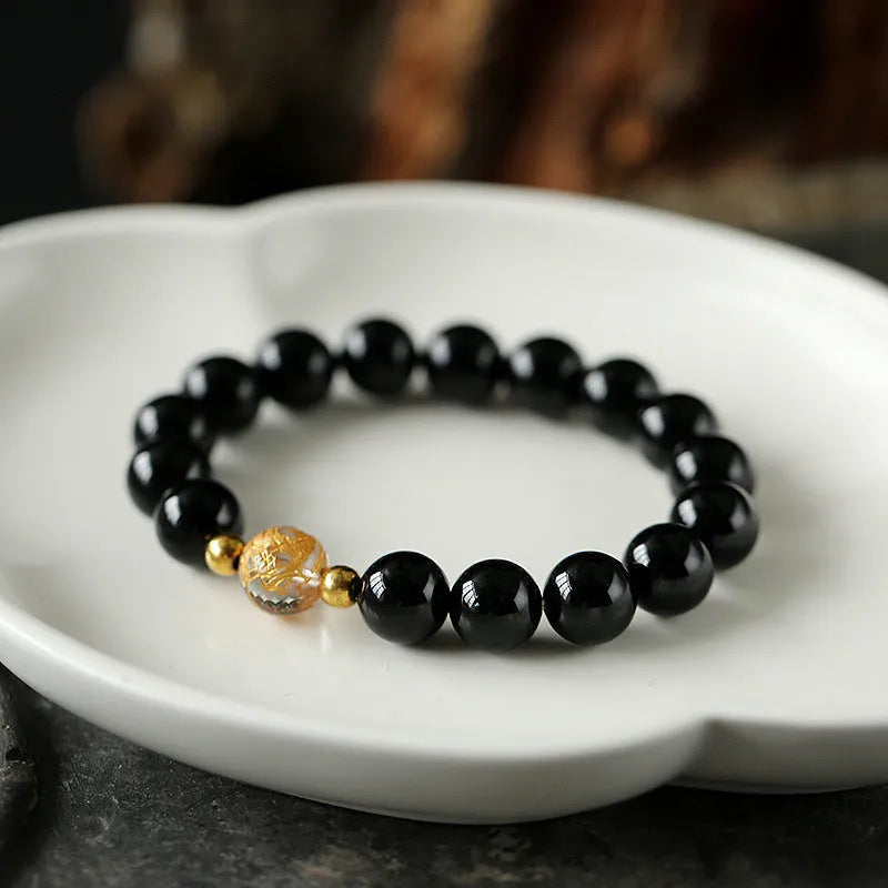 Geometric unisex bracelet with black obsidian agate beads, white crystal beads, and a golden dragon crystal focal bead.
