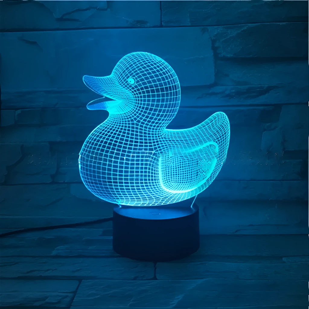 Little Yellow Duck 3D night light showing seven LED colours on a tabletop with remote control.