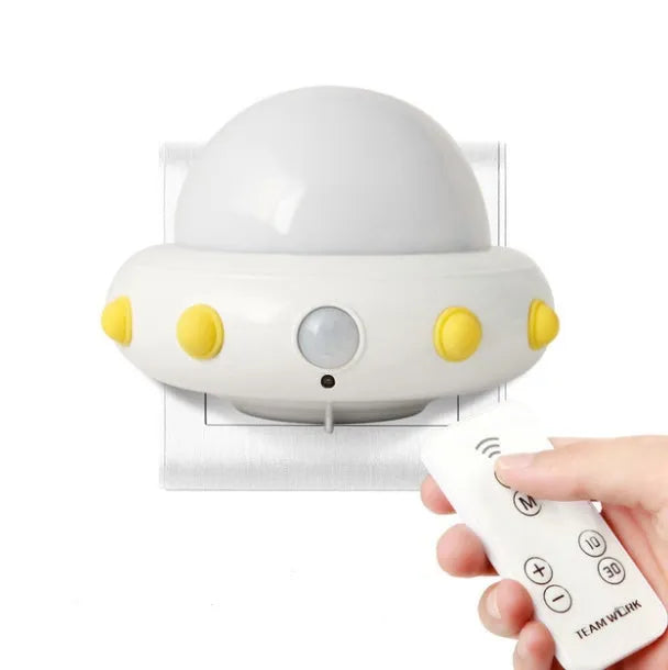Blue UFO-shaped bedside night light with remote control on a table.