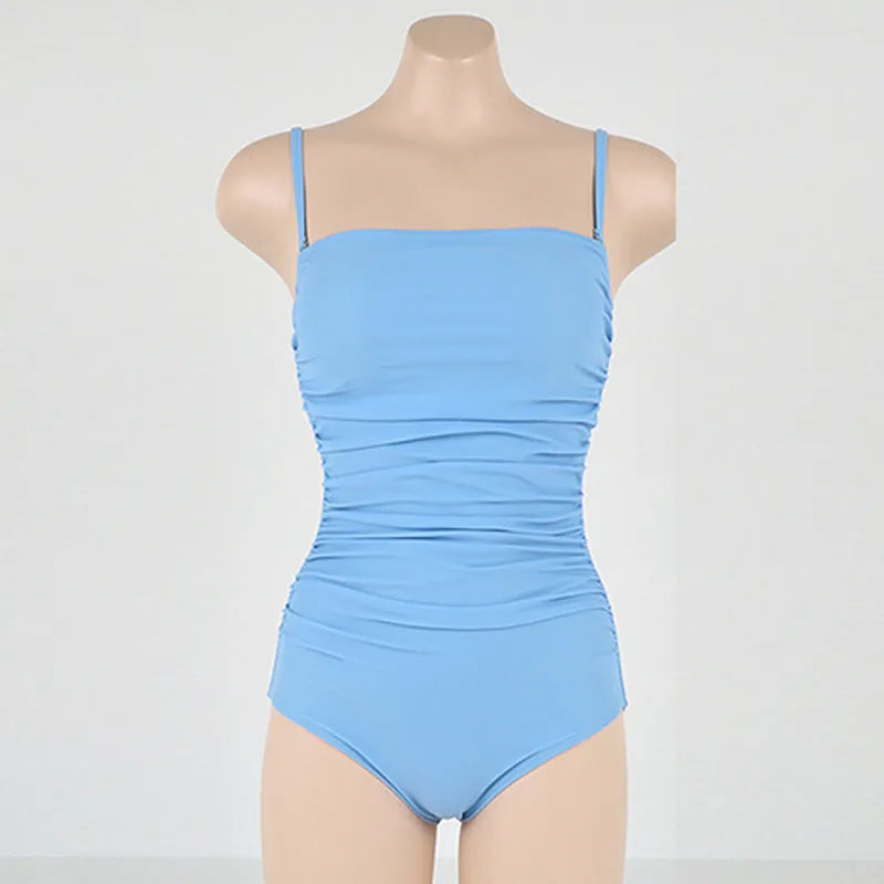 Sling style one-piece swimsuit with belly pleating in a solid colour.