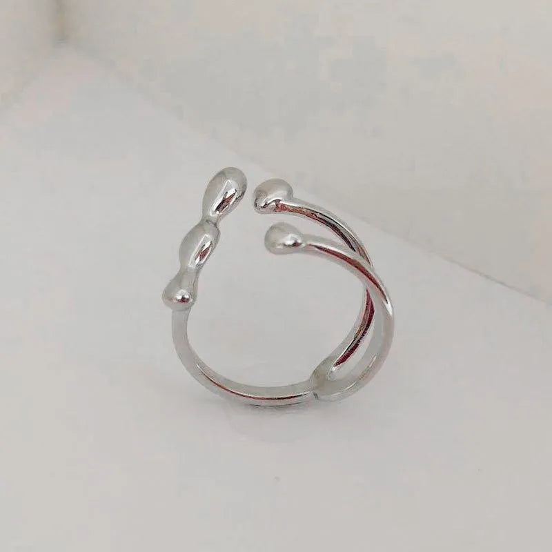 Gold or silver brass opening ring with spherical design elements on a model's finger.
