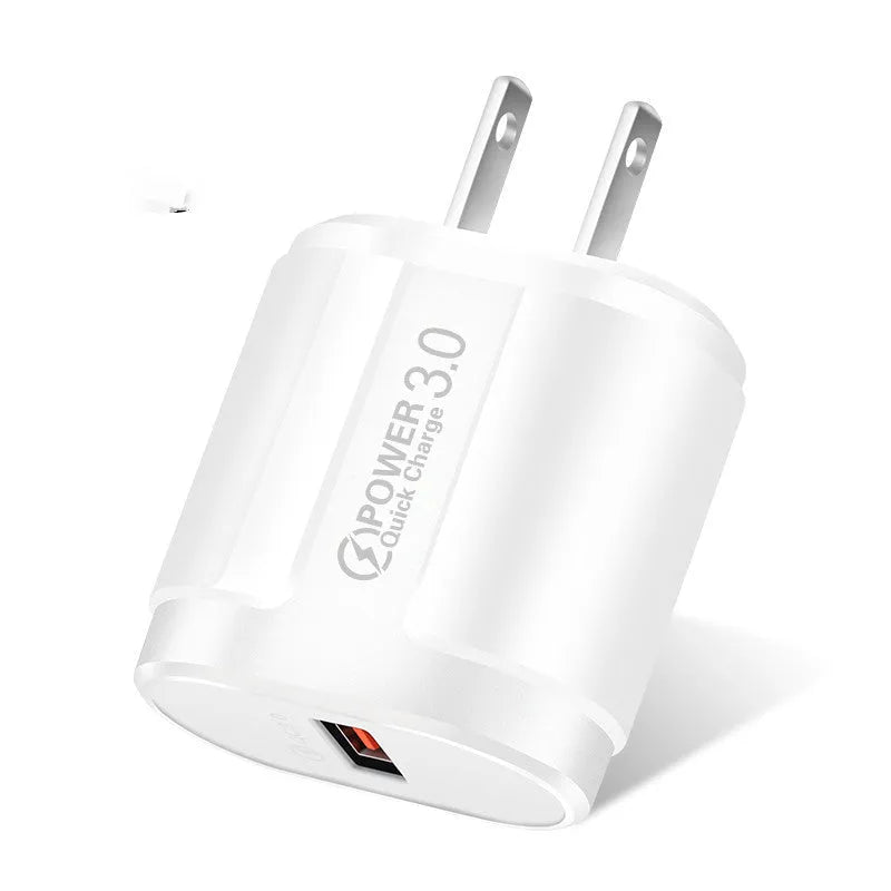 Compact white international travel phone charger with UK, US, and EU plug adapters on a desk