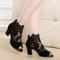 Black lace gladiator sandals with a square high heel and peep toe on a woman's foot