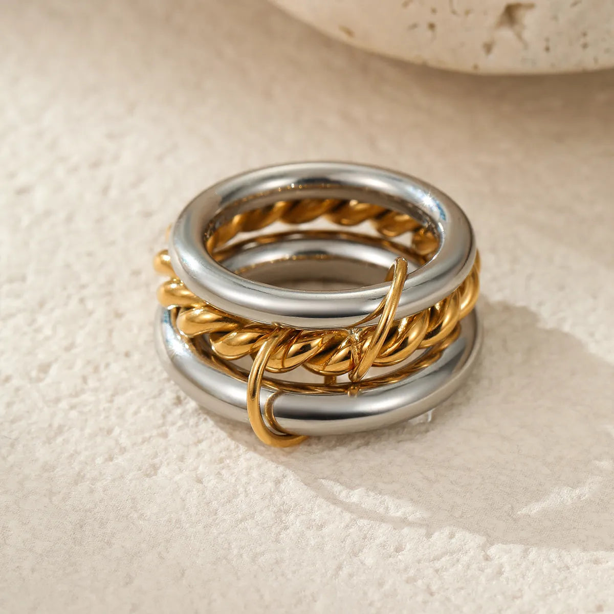 Stacked gold plated stainless steel ring set showing exaggerated design on a model's hand.
