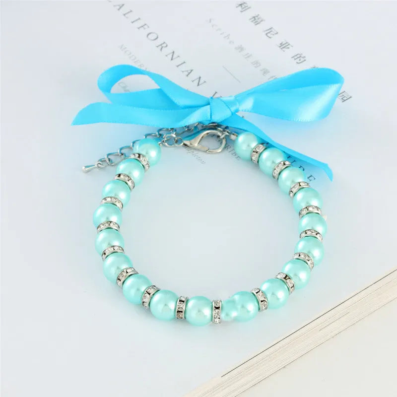 Adjustable diamond dog pearl necklace with rhinestones and ribbon bow in blue, pink, purple, or white.