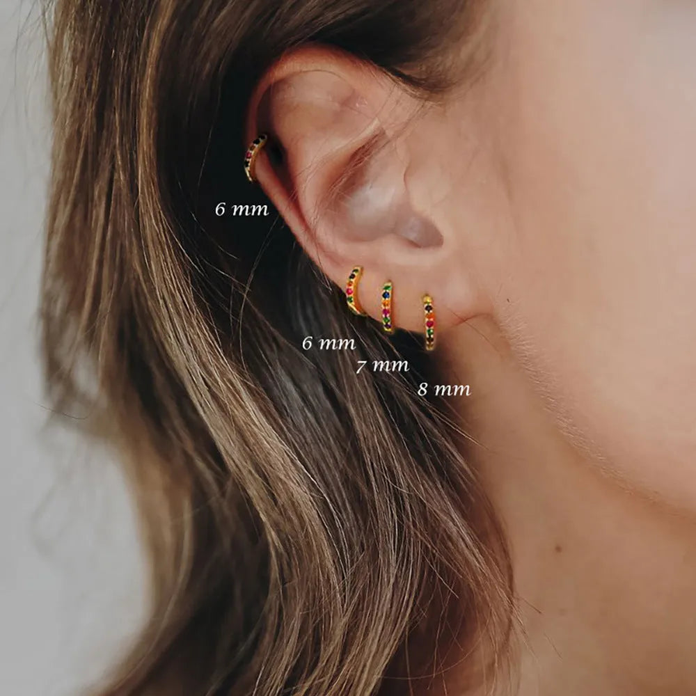 Gold, rose gold, and silver coloured geometric circle stud earrings with a perforated centre on a white background.